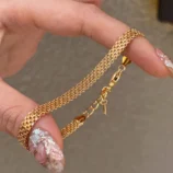 Gold stainless steel chain braided bracelet held in hand