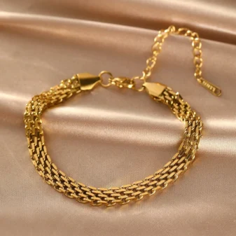 Gold stainless steel chain braided bracelet resting on silk fabric