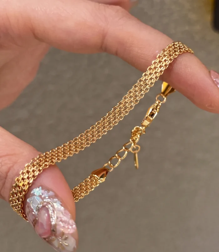 Gold stainless steel chain braided bracelet held in hand