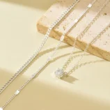 Gold and silver layered zircon pendant necklace silver close-up on stone prop