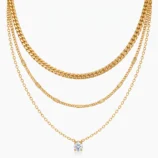 Gold and silver layered zircon pendant necklace draped over white circular prop