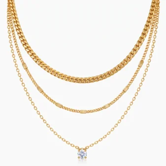 Gold and silver layered zircon pendant necklace draped over white circular prop