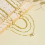 Gold and silver layered zircon pendant necklace laid flat on stone display