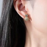 Gold & Silver Zircon Stud Earrings worn securely on a woman's earlobe.