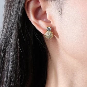 Gold & Silver Zircon Stud Earrings worn securely on a woman's earlobe.