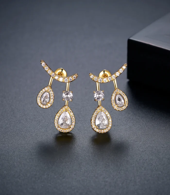 Gold & Silver Zircon Water Drop Earrings in gold close-up on a dark display.