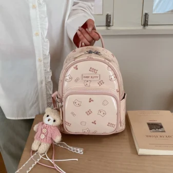 Pastel Cat Print PU Leather Backpack for Women held by hand indoors.
