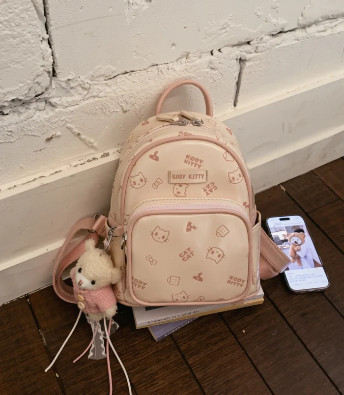 Pastel Cat Print PU Leather Backpack for Women light pink version resting on floor.