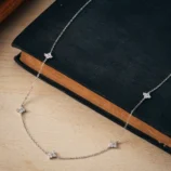 A beautifully crafted silver minimalist rhinestone necklace resting on a dark surface.