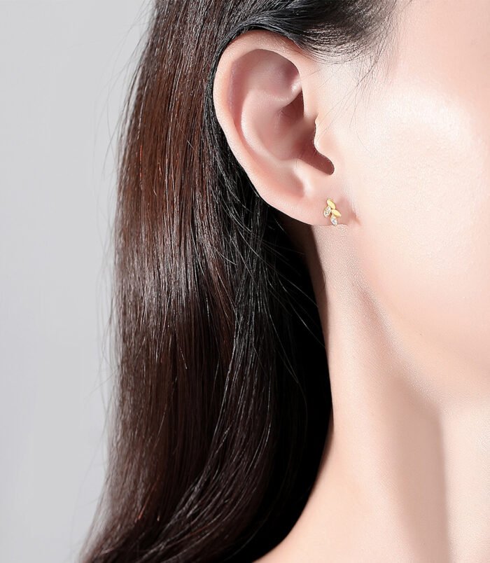 Sterling silver leaf earrings worn on the earlobe by a model.