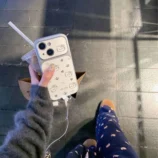 White Lambskin Hello Kitty Mirror Phone Case held in hand outdoors.