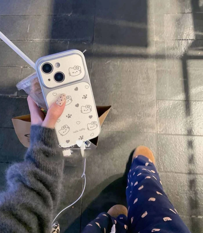 White Lambskin Hello Kitty Mirror Phone Case held in hand outdoors.