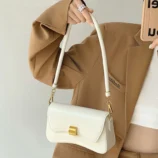 Black & White PU Leather Baguette Bag for Women worn on the shoulder in white.