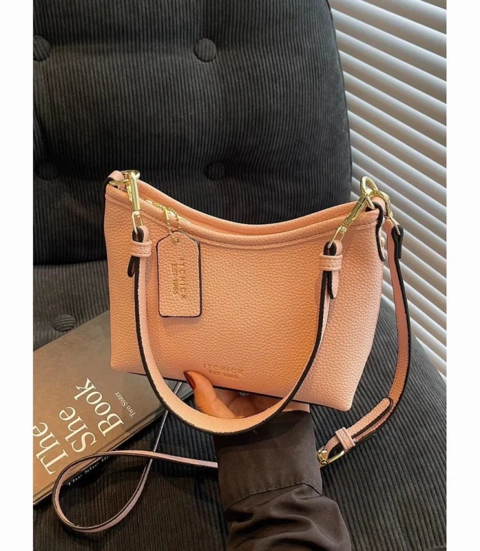 Pink everyday bag displayed sitting on a book to show structure