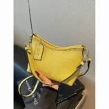 Yellow shoulder purse held up while worn across the body