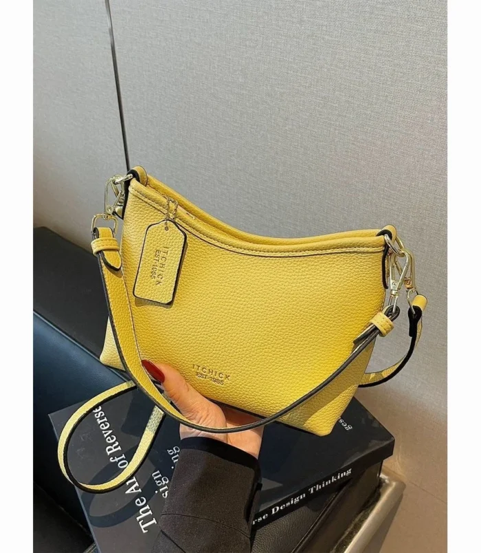 Yellow shoulder purse held up while worn across the body