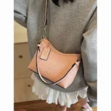 Pink dumpling style bag worn across the body showing strap details