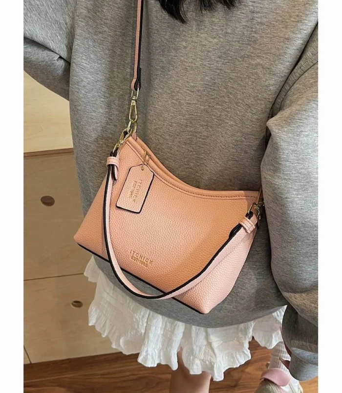 Pink dumpling style bag worn across the body showing strap details