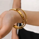 Elegant gold double loop bracelet worn elegantly on a woman's wrist.