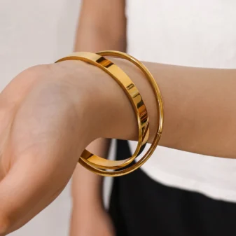 Elegant gold double loop bracelet worn elegantly on a woman's wrist.