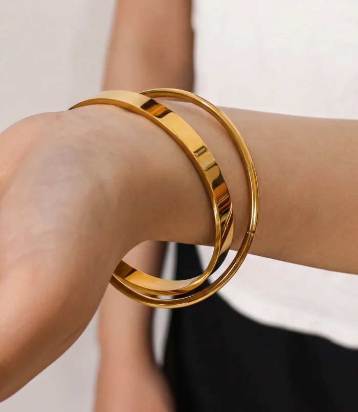 Elegant gold double loop bracelet worn elegantly on a woman's wrist.