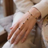 Elegant gold-plated heart finger bracelet worn gently on a model's hand view of the black gemstone chain