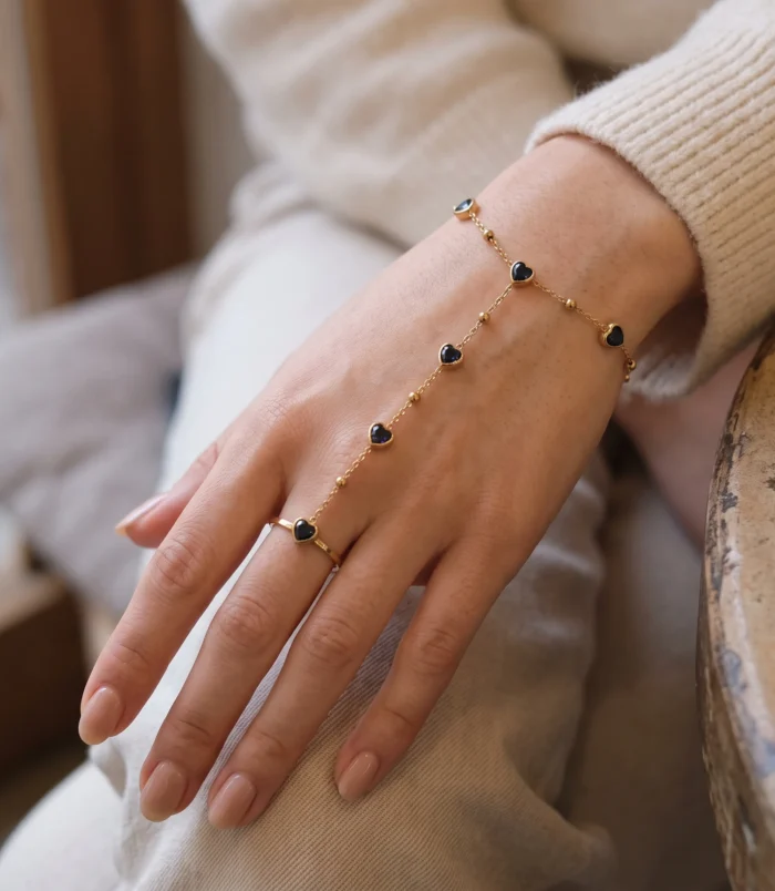 Elegant gold-plated heart finger bracelet worn gently on a model's hand view of the black gemstone chain