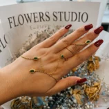 Beautiful rhinestone finger bracelet in gold with green stones worn on hand.