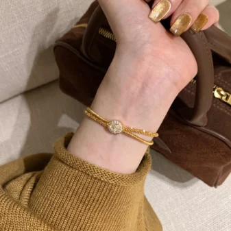 Elegant gold wire wrapped bracelet worn gracefully on a woman's wrist.