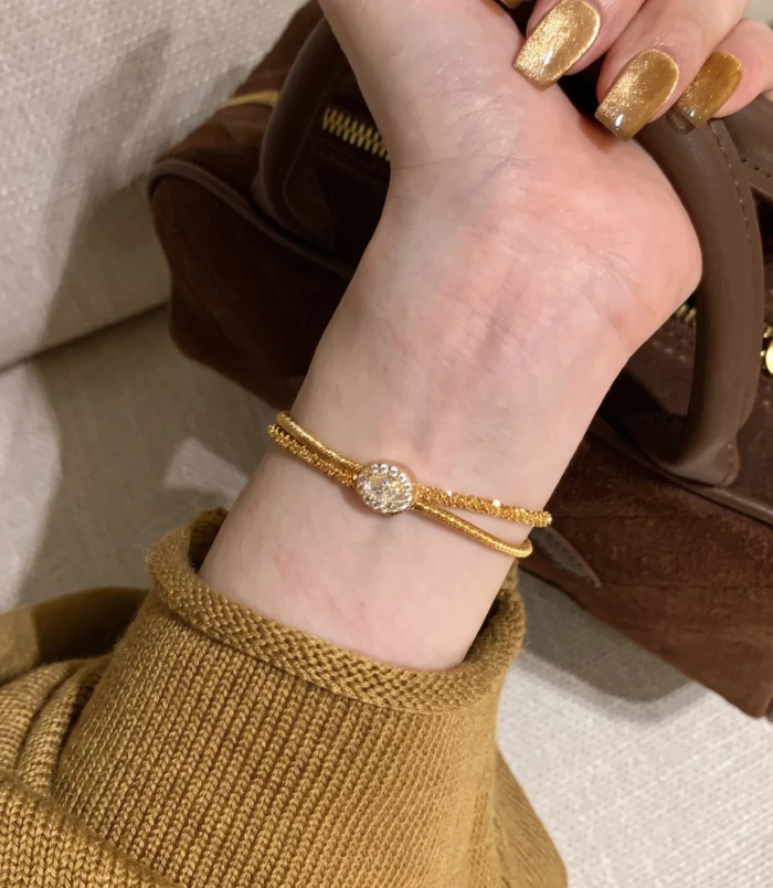 Elegant gold wire wrapped bracelet worn gracefully on a woman's wrist.