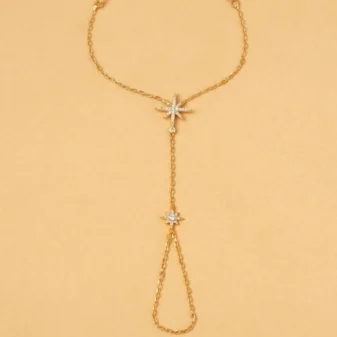 Flat lay front view of the gold star rhinestone finger bracelet on a neutral background