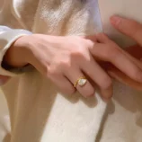 Gold Teardrop Zircon Ring worn on finger near a blue velvet ring box.