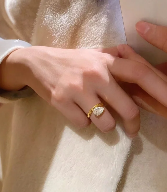 Gold Teardrop Zircon Ring worn on finger near a blue velvet ring box.
