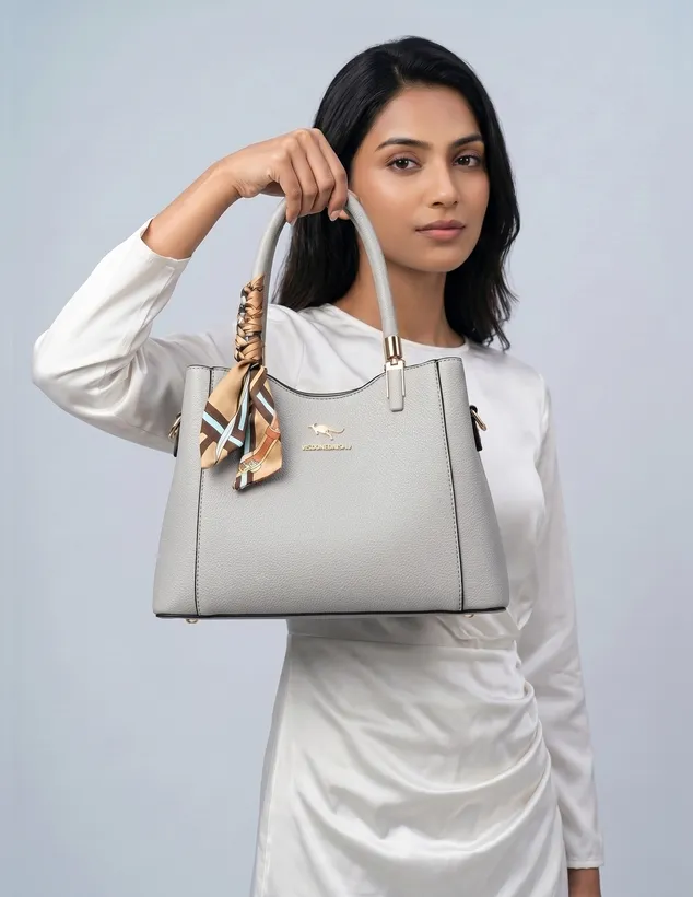 Woman holding a light grey handbag with a silk scarf on the handle