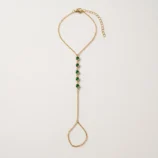 Multicolour rhinestone finger bracelet for women flat lay showing gold plating and green stones.
