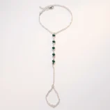 Multicolour rhinestone finger bracelet for women flat lay displaying silver finish and green stones.