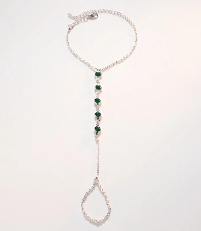 Multicolour rhinestone finger bracelet for women flat lay displaying silver finish and green stones.