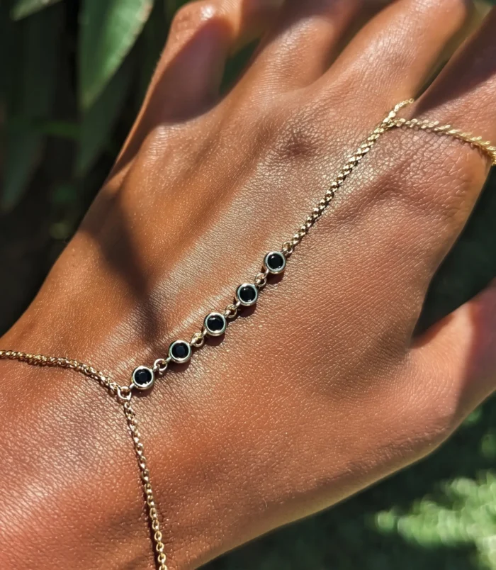 Multicolour rhinestone finger bracelet for women worn on hand featuring black stone accents.