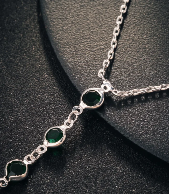 Multicolour rhinestone finger bracelet for women close-up view of the silver connecting chain and green stones.