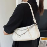 Elegant beige pleated chain shoulder bag styled with a black outfit.