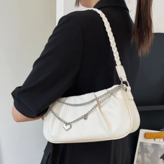 Elegant beige pleated chain shoulder bag styled with a black outfit.