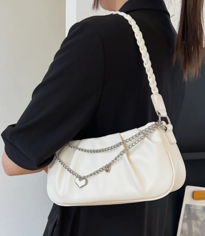 Elegant beige pleated chain shoulder bag styled with a black outfit.