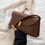 Light brown daily wear bag held gracefully against a coat