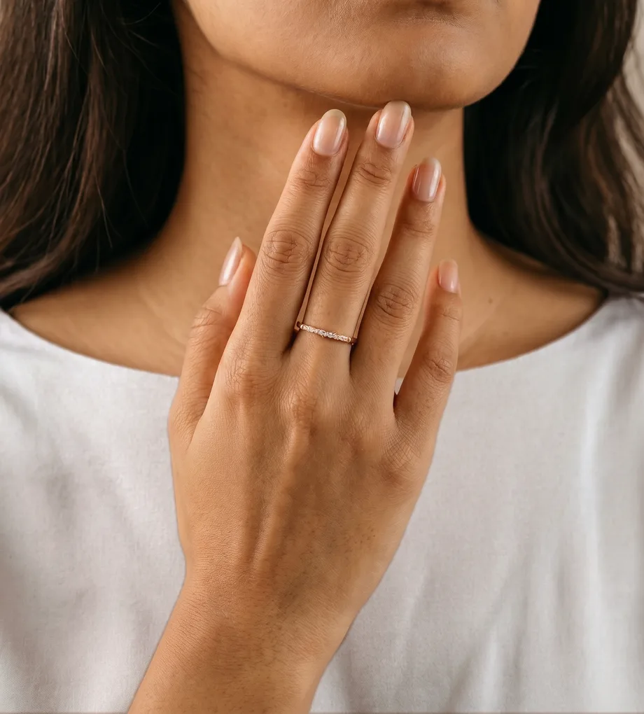 Woman wearing a rose gold band ring with small clear crystals