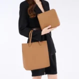 Solid Colour PU Leather Tote Bag for Women with model holding both the main bag and included pouch.
