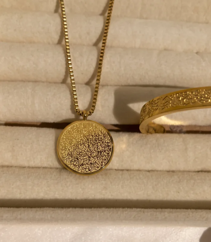 Beautiful gold etched oval necklace resting on a soft display tray.