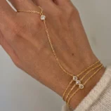 Elegant gold three-layer finger bracelet worn gracefully on a woman's hand.