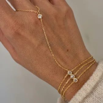 Elegant gold three-layer finger bracelet worn gracefully on a woman's hand.