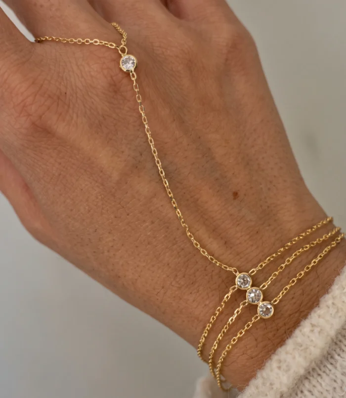 Elegant gold three-layer finger bracelet worn gracefully on a woman's hand.